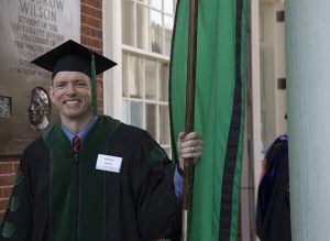 James H. Moak, MD, RDMS, leading the procession with the UVA School of Medicine green flag.