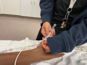 Student inserting IV in sim center mannequin