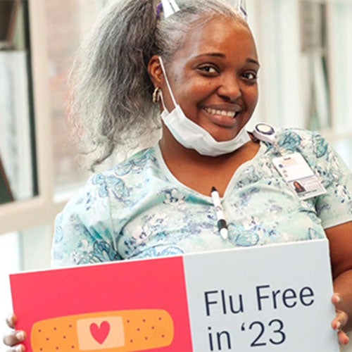 Woman holding sign Flu Free in '23