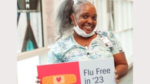 Woman holding sign Flu Free in '23
