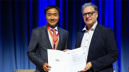 Albert S. Jun, MD, PhD, receiving the Keynote Speaker certificate from the President of the German Ophthalmology Society, Professor Gerd Auffarth, from the University of Heidelberg.