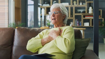 Woman clutching her chest; signs of a heart attack