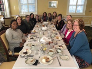 Faculty around a large table eating lunch.